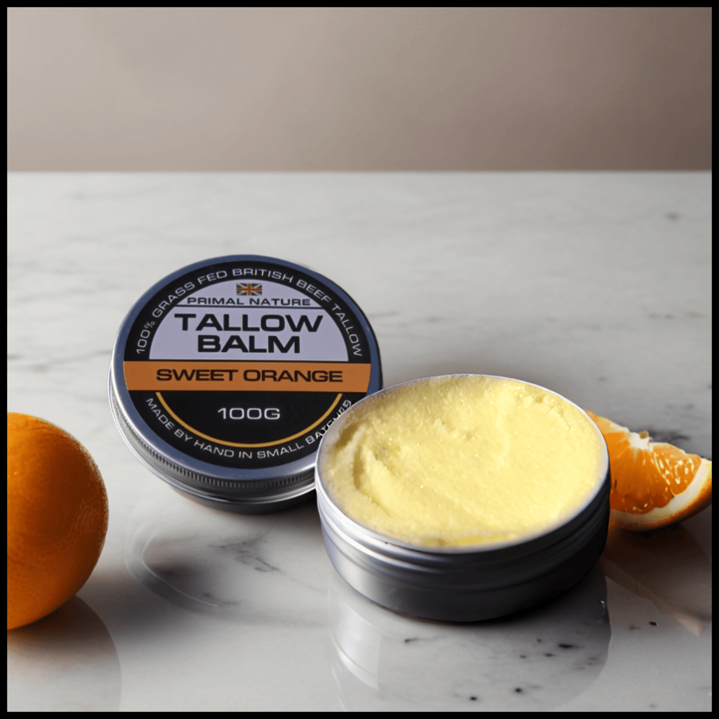 Grass-Fed Tallow Balm | Unscented | Sweet Orange | Sandalwood | 100g in tin with orange slice on a marble surface.